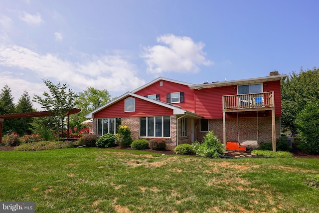 back of property with a balcony, a lawn, and brick siding