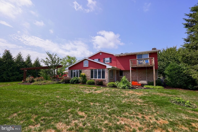 rear view of house with a yard, brick siding, and a balcony