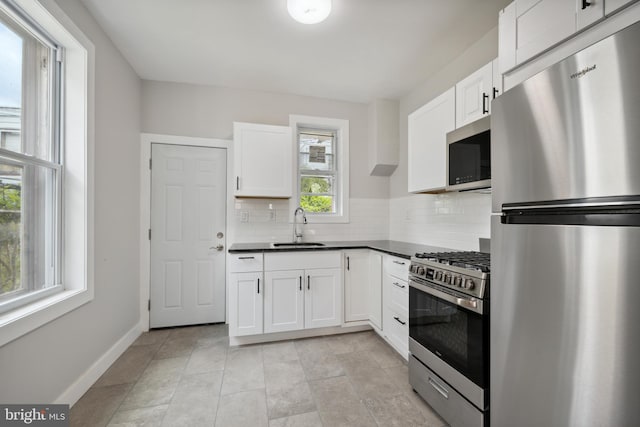 kitchen featuring light tile patterned floors, appliances with stainless steel finishes, white cabinets, sink, and tasteful backsplash