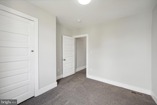 unfurnished bedroom featuring dark colored carpet and a closet