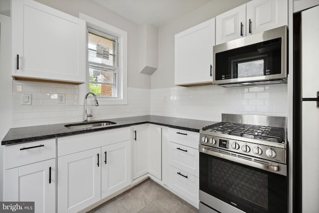 kitchen featuring light tile patterned floors, appliances with stainless steel finishes, backsplash, sink, and white cabinetry