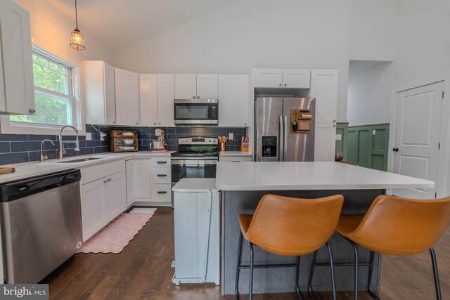 kitchen with hanging light fixtures, a kitchen island, appliances with stainless steel finishes, and white cabinets