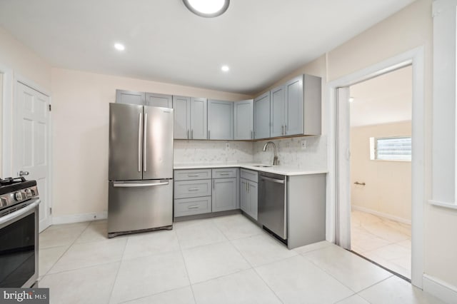 kitchen with sink, gray cabinetry, light tile patterned floors, stainless steel appliances, and decorative backsplash