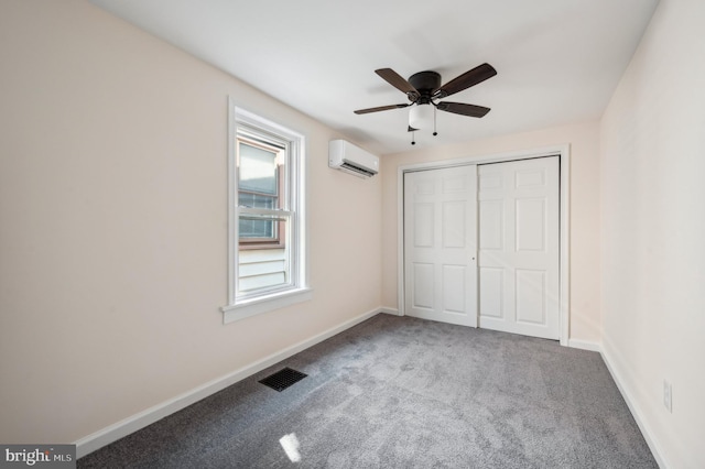 unfurnished bedroom with a closet, carpet floors, an AC wall unit, and ceiling fan