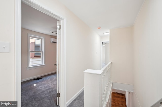 hallway featuring a wall mounted AC and dark carpet