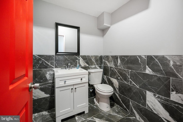 bathroom with tile patterned floors, tile walls, vanity, and toilet