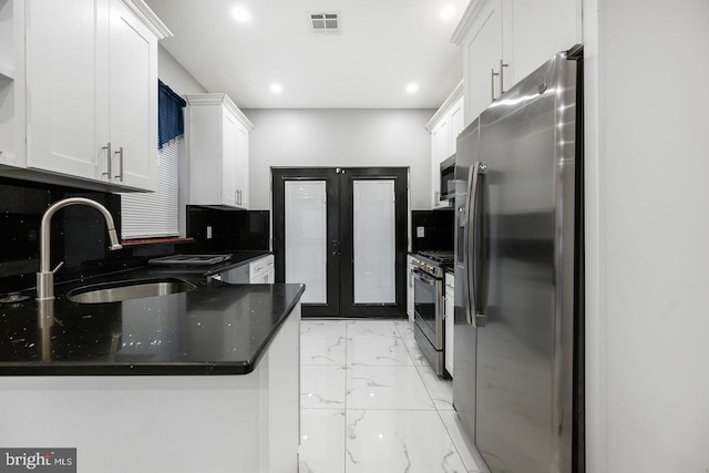 kitchen with appliances with stainless steel finishes, white cabinetry, light tile patterned floors, sink, and kitchen peninsula