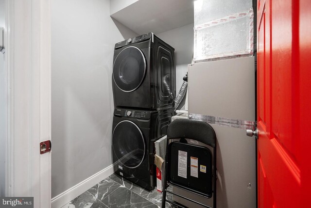 laundry room featuring dark tile patterned floors and stacked washer / dryer