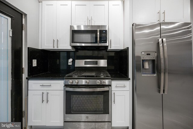 kitchen with appliances with stainless steel finishes, white cabinets, decorative backsplash, and dark stone countertops