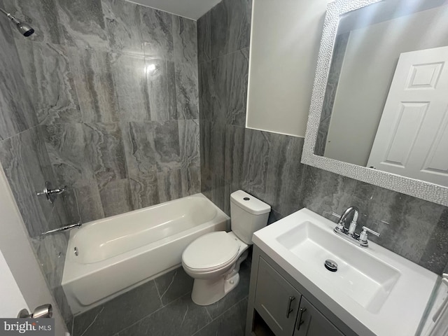 full bathroom with vanity, tile patterned floors, tile walls, tiled shower / bath combo, and toilet