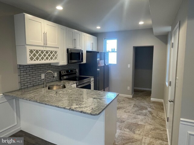 kitchen featuring appliances with stainless steel finishes, white cabinetry, kitchen peninsula, and sink