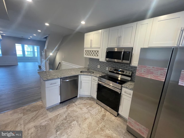 kitchen with white cabinetry, stainless steel appliances, light hardwood / wood-style floors, and light stone counters