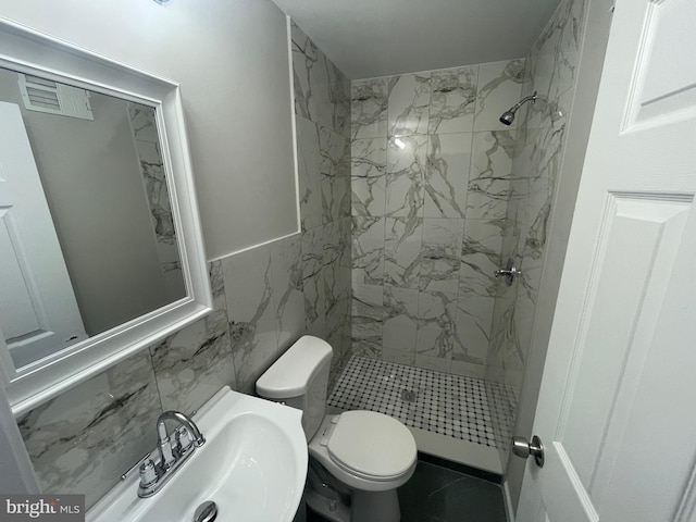 bathroom with sink, tile walls, a tile shower, tile patterned flooring, and toilet