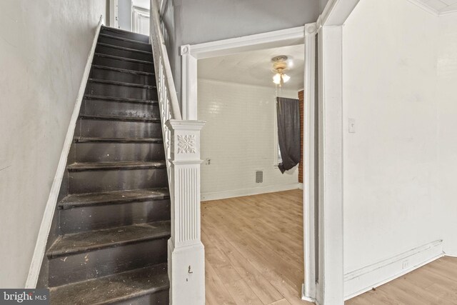 staircase with light hardwood / wood-style floors and crown molding