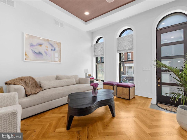 living room with light parquet flooring and a tray ceiling