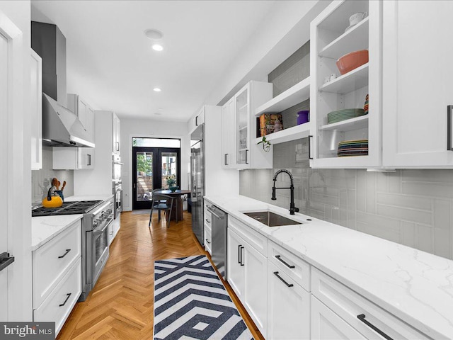 kitchen with white cabinets, sink, light parquet floors, premium appliances, and wall chimney exhaust hood