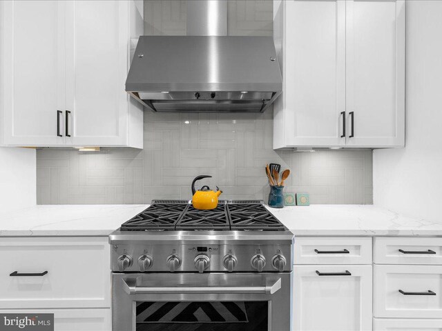 kitchen featuring decorative backsplash, high end stainless steel range, light stone counters, and wall chimney range hood