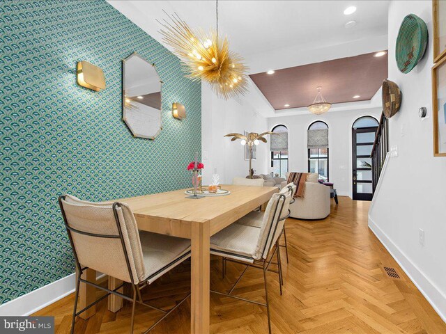 dining room featuring a notable chandelier and light parquet flooring