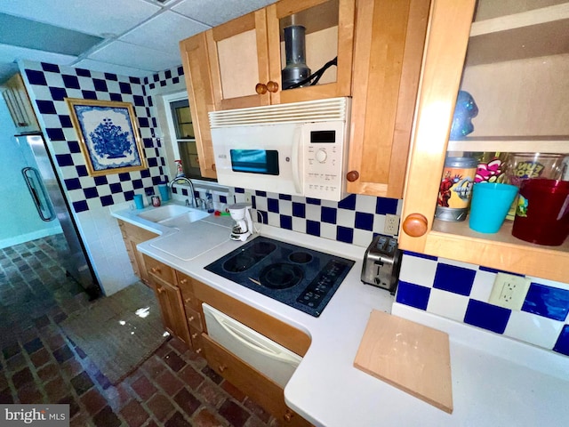 kitchen featuring white microwave, tasteful backsplash, a paneled ceiling, black electric cooktop, and a sink