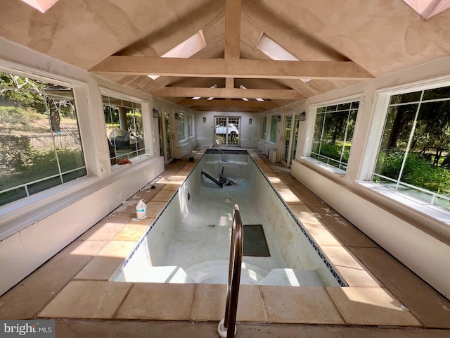 unfurnished sunroom featuring vaulted ceiling with skylight and plenty of natural light