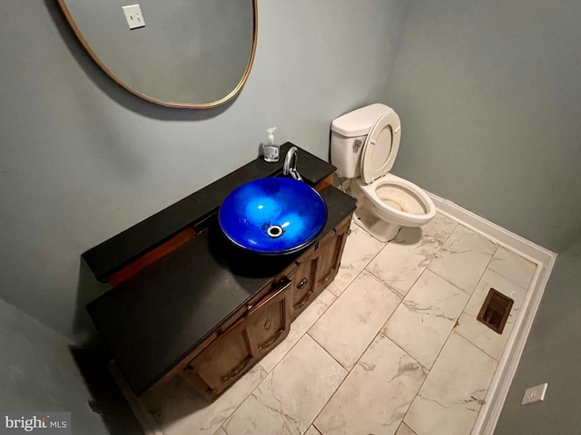 bathroom featuring baseboards, toilet, marble finish floor, and vanity