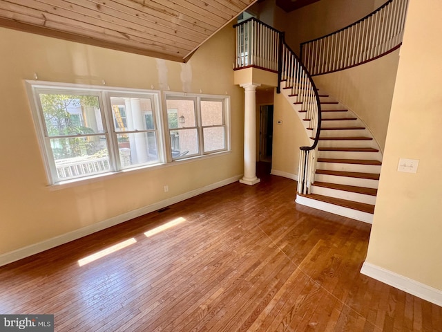 unfurnished living room with a high ceiling, hardwood / wood-style flooring, decorative columns, and wooden ceiling