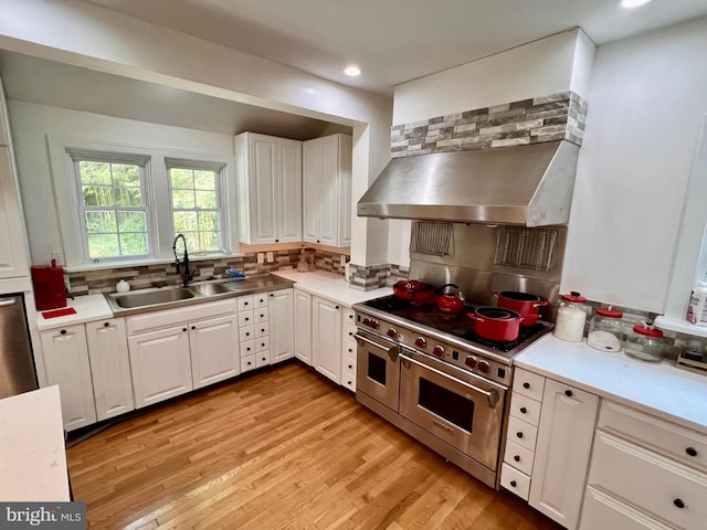 kitchen featuring white cabinets, tasteful backsplash, light hardwood / wood-style flooring, extractor fan, and range with two ovens