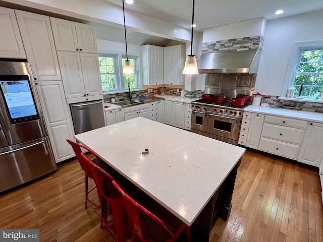 kitchen with appliances with stainless steel finishes, hanging light fixtures, a center island, sink, and plenty of natural light