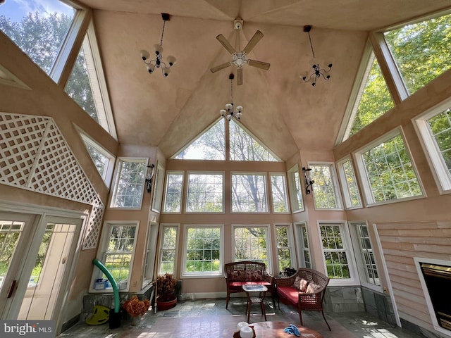 sunroom / solarium with ceiling fan with notable chandelier and a fireplace