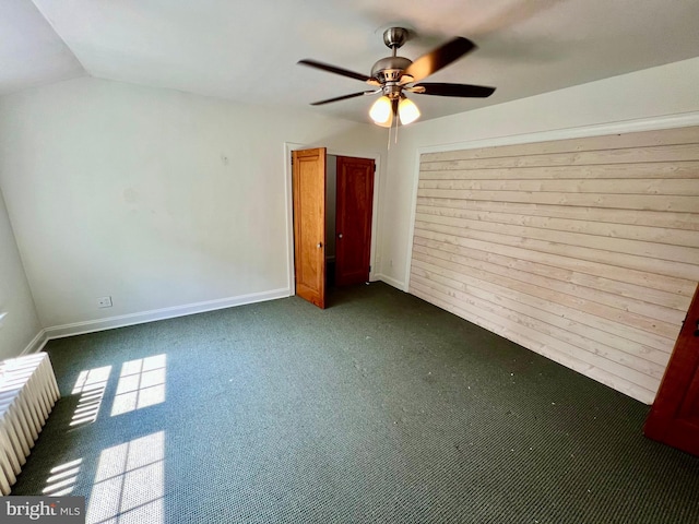 unfurnished bedroom featuring ceiling fan, vaulted ceiling, and dark carpet