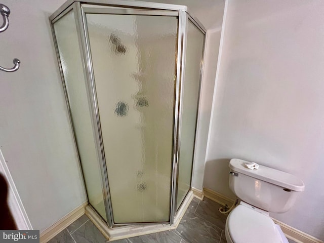 bathroom featuring a shower with door and toilet