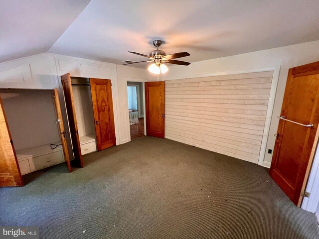 unfurnished bedroom featuring ceiling fan, lofted ceiling, and dark carpet