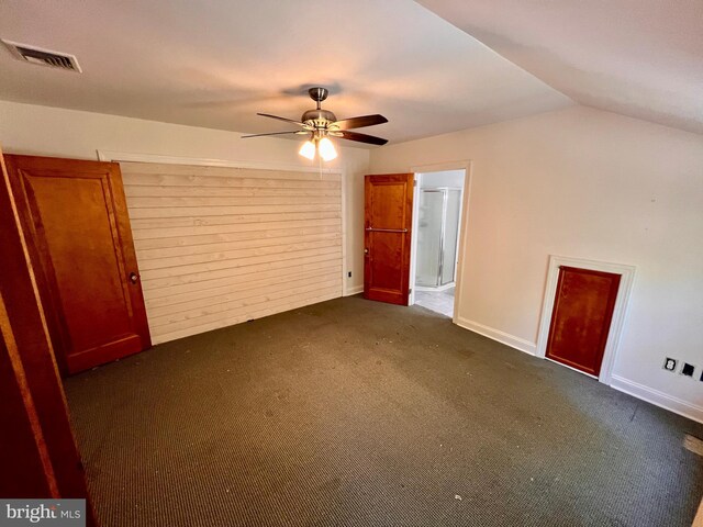 unfurnished bedroom featuring dark colored carpet, vaulted ceiling, and ceiling fan