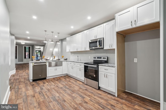 kitchen with sink, stainless steel appliances, light stone counters, white cabinets, and decorative light fixtures