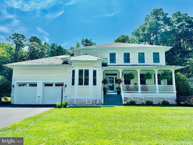 view of front of property featuring covered porch, a garage, and a front yard