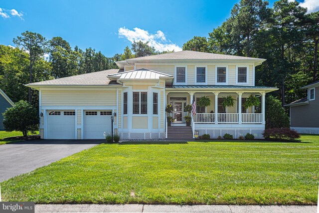 view of front of house featuring a front lawn, a garage, and covered porch