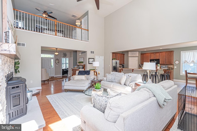 living area featuring baseboards, visible vents, ceiling fan, and light wood finished floors