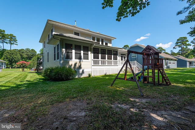 exterior space featuring a sunroom, a playground, and a lawn