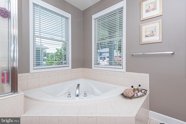 bathroom with a garden tub and baseboards