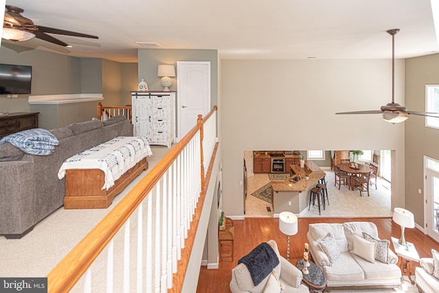 living area with visible vents, ceiling fan, baseboards, and wood finished floors