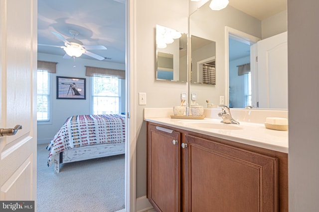 bathroom with baseboards, ensuite bath, vanity, and a ceiling fan