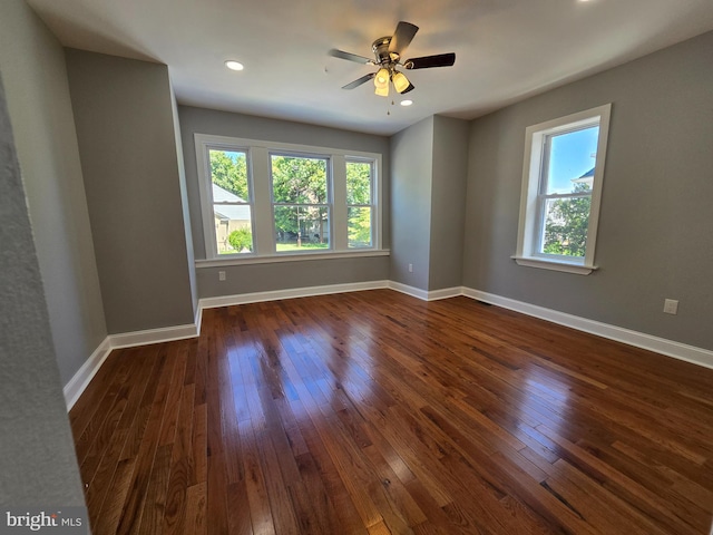 empty room with plenty of natural light, ceiling fan, and dark hardwood / wood-style flooring