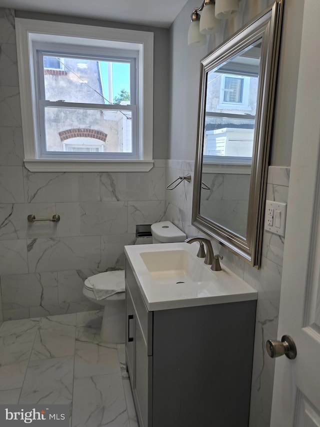 bathroom featuring vanity, toilet, and tile walls