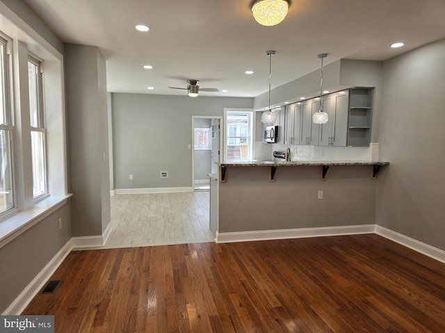 kitchen with hardwood / wood-style flooring, plenty of natural light, a breakfast bar area, and kitchen peninsula