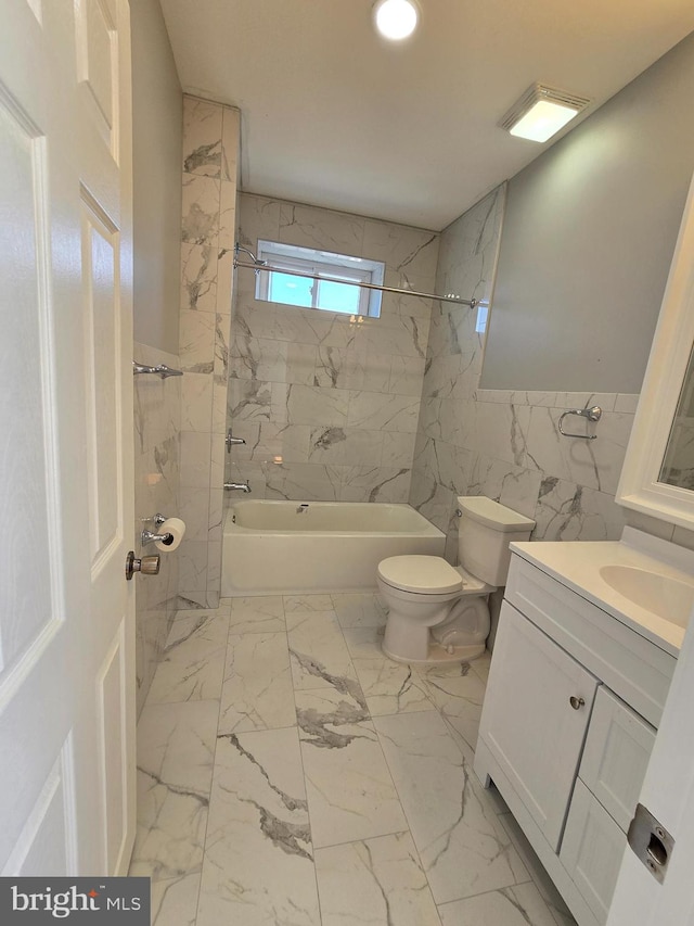 full bathroom with tiled shower / bath combo, tile walls, toilet, and vanity