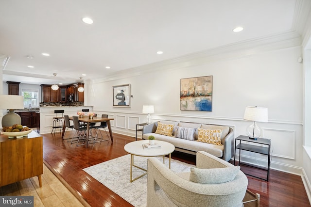 living room with hardwood / wood-style flooring, crown molding, and sink