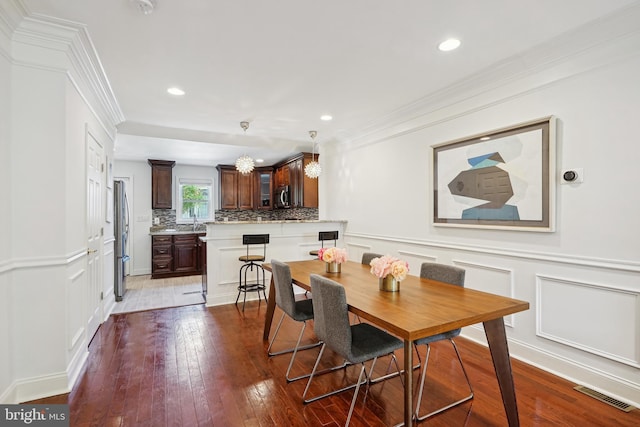 dining room featuring sink, light hardwood / wood-style flooring, and ornamental molding