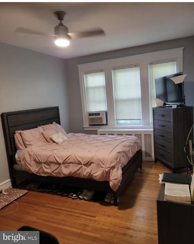 bedroom featuring cooling unit, ceiling fan, and light wood-type flooring