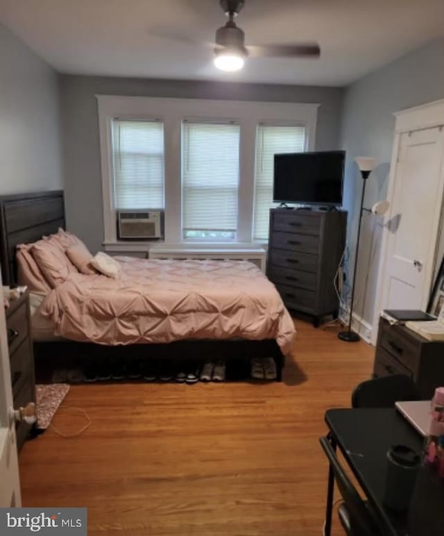 bedroom with cooling unit, hardwood / wood-style flooring, and ceiling fan