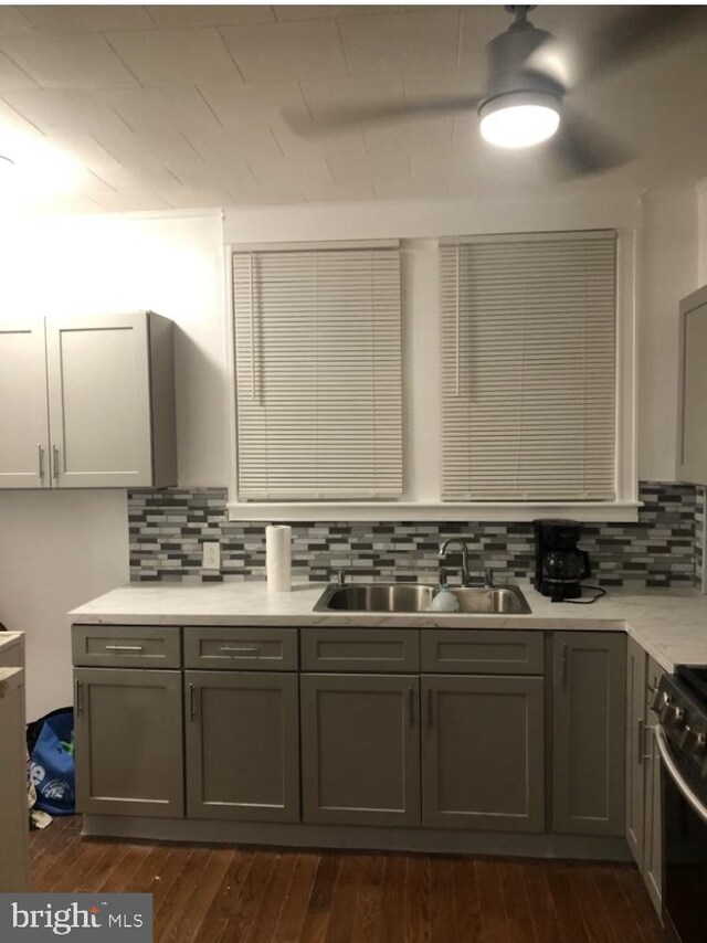 kitchen with sink, gray cabinetry, dark hardwood / wood-style flooring, decorative backsplash, and range